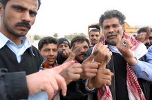 Iraqi police officers hold up their index fingers marked with purple indelible ink, a security measure to prevent double voting.