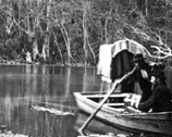 Photographer with large camera in rowboat.